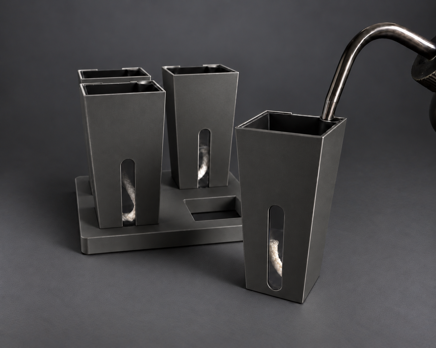 Black small self-watering cups with one cup removed from the base and the watering nozzle seated in the inner pot corner opening