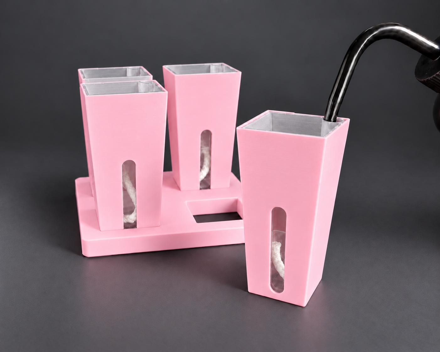 Silk Pink small self-watering cups with one cup removed from the base and the watering nozzle seated in the inner pot corner opening