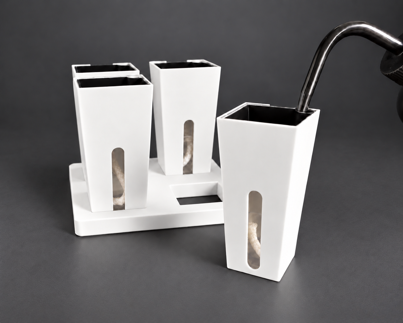 White small self-watering cups with one cup removed from the base and the watering nozzle seated in the inner pot corner opening